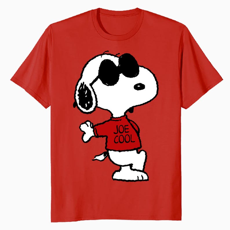 May include: A bright red short-sleeved t-shirt featuring a graphic of the cartoon character Snoopy wearing black sunglasses and a red shirt with the text JOE COOL printed in black. The character is white with black ears and outlines.