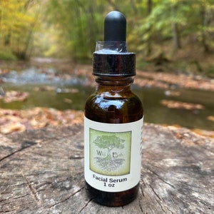 May include: A brown glass bottle with a black dropper top and a white label that reads "Wild Earth Facial Serum 1 oz".