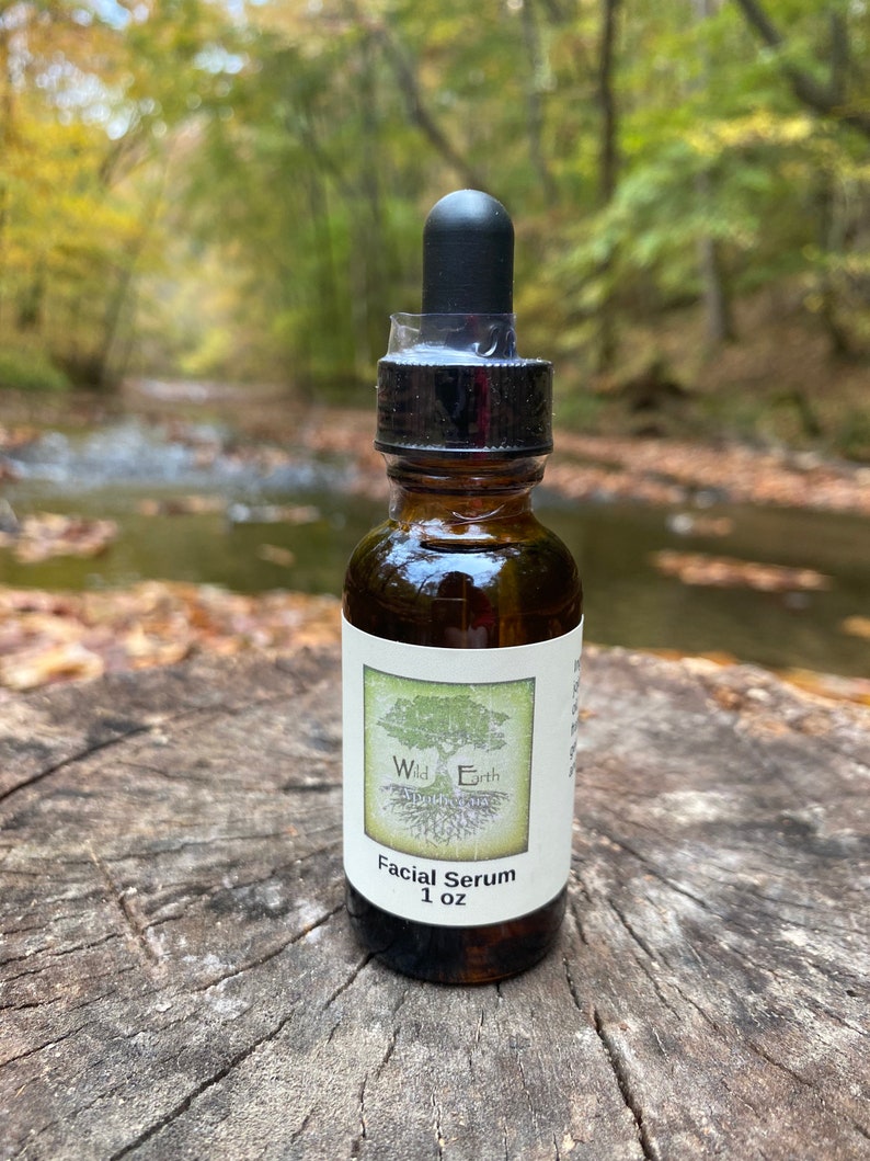 May include: A brown glass bottle with a black dropper top and a white label that reads "Wild Earth Facial Serum 1 oz".