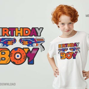 May include: A white t-shirt with a colorful graphic design that says "Birthday Boy" with toy guns on either side of the text. The design is in a cartoon style with bright colors and bold lines.