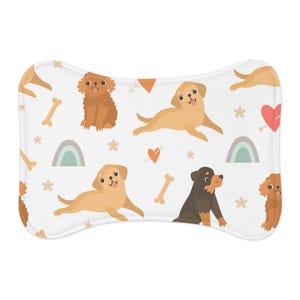 Puede incluir: Cama para mascotas con forma de hueso, con un fondo blanco y un patrón repetido de perros de dibujos animados en varias poses. Los perros son de tonos marrones y beige, con corazones, huesos, arcoíris y flores.