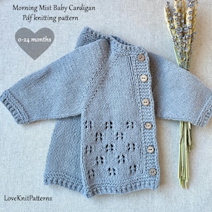 Puede incluir: Un cárdigan azul claro para bebé con botones de madera. El suéter de punto tiene un patrón calado decorativo en la parte delantera y está diseñado para bebés de 0 a 24 meses. El texto "Morning Mist Baby Cardigan Pdf knitting pattern" es visible.