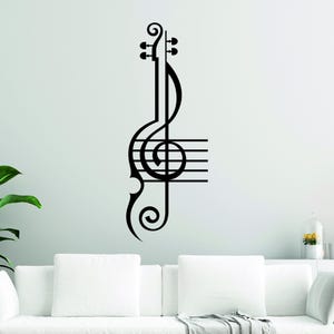 Pu&ograve; includere: Adesivo da parete nero e bianco con chiave di violino e pentagramma. L'adesivo presenta una chiave di violino stilizzata con una nota musicale e cinque linee del pentagramma.