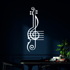 Pu&ograve; includere: Decalcomania da parete bianca di chiave di violino e note musicali su una parete blu scuro. Il decalcomania &egrave; una rappresentazione stilizzata di uno strumento musicale con una chiave di violino e note musicali.