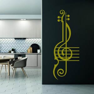 Pu&ograve; includere: Un adesivo da parete dorato a forma di chiave di violino e pentagramma. L'adesivo &egrave; su una parete grigio scuro in un ambiente da cucina.
