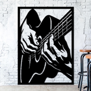 May include: Black metal wall art depicting a musician playing a guitar. The silhouette shows hands on the fretboard and strings. The artwork is framed and mounted on a white brick wall, with a bar and stools in the background.