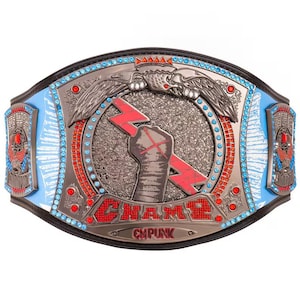 Puede incluir: Un cinturón de campeonato de lucha libre azul y plateado con detalles rojos. El cinturón presenta un rayo estilizado y un puño con el texto "CHAMP" y "CM PUNK".
