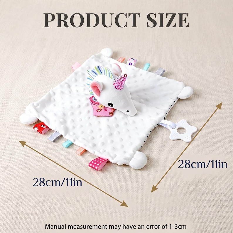 Puede incluir: Una manta de seguridad para beb&eacute; blanca con una cabeza de unicornio de peluche y cintas de colores. La manta mide 28 cm por 28 cm y tiene una superficie texturizada. Un mordedor en forma de estrella est&aacute; adjunto.