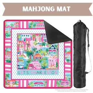 May include: A colorful Mahjong mat with a Charleston theme, featuring pink, blue, and white accents. The mat displays illustrations of houses, palm trees, and the text "LET'S CHARLESTON." Includes a black carrying bag.