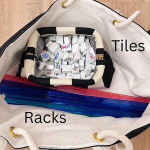 May include: A black and white tote bag containing a black and white zippered pouch filled with white Mahjong tiles and several translucent red and blue 19-inch racks. Text reads: Room For Your Mahjong Essentials, Tiles, Racks, Actual Photo of 19" racks and Tiles in Bag.