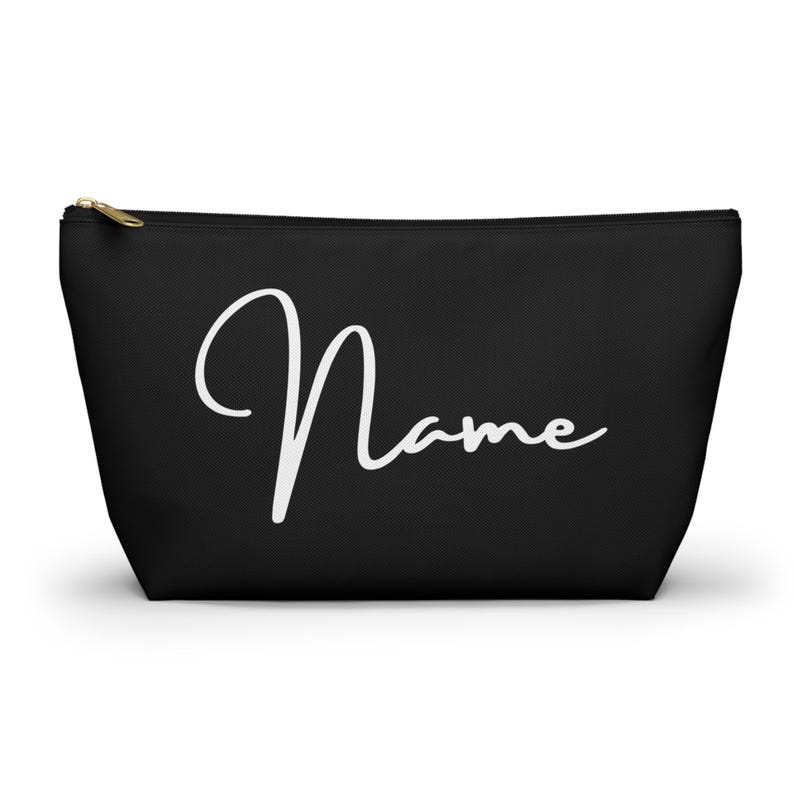 以下が含まれることがあります： 白い筆記体で「Name」と書かれた、黒いジッパー付きの化粧ポーチです。