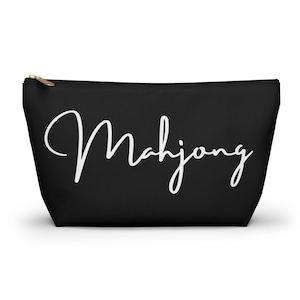 May include: Black zippered makeup bag with the word "Mahjong" written in white cursive script.