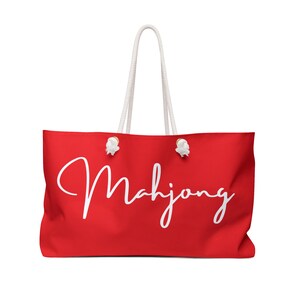 Puede incluir: Bolsa de lona roja con asas de cuerda blanca y la palabra "Mahjong" escrita en cursiva blanca.