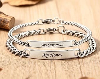 May include: Two silver-toned metal chain bracelets featuring flat rectangular identification plates. The top plate is engraved with the text My Superman, and the bottom plate is engraved with the text My Honey. Both bracelets have lobster claw clasps.