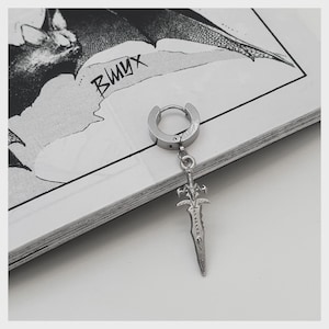May include: A silver-colored earring with a sword pendant. The earring has a hoop design with a hinged closure. The sword pendant is detailed with a hilt and blade design. The earring is displayed on a black and white illustrated surface.