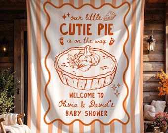 Könnte beinhalten: Ein rechteckiges Stoffbanner mit vertikalen orange-weißen Streifen und einem zentralen weißen Feld mit gewelltem orangefarbenem Rand. Der Text lautet: our little CUTIE PIE is on the way, WELCOME TO Olivia & David's BABY SHOWER, ergänzt durch eine Kürbiskuchen-Grafik.