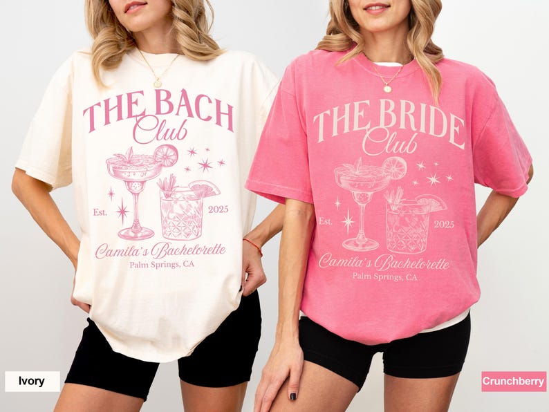 May include: Two white t-shirts with pink text and graphics. The text on the left shirt reads "The Bach Club" and the text on the right shirt reads "The Bride Club". Both shirts feature a cocktail glass with a lime wedge and a starburst design.
