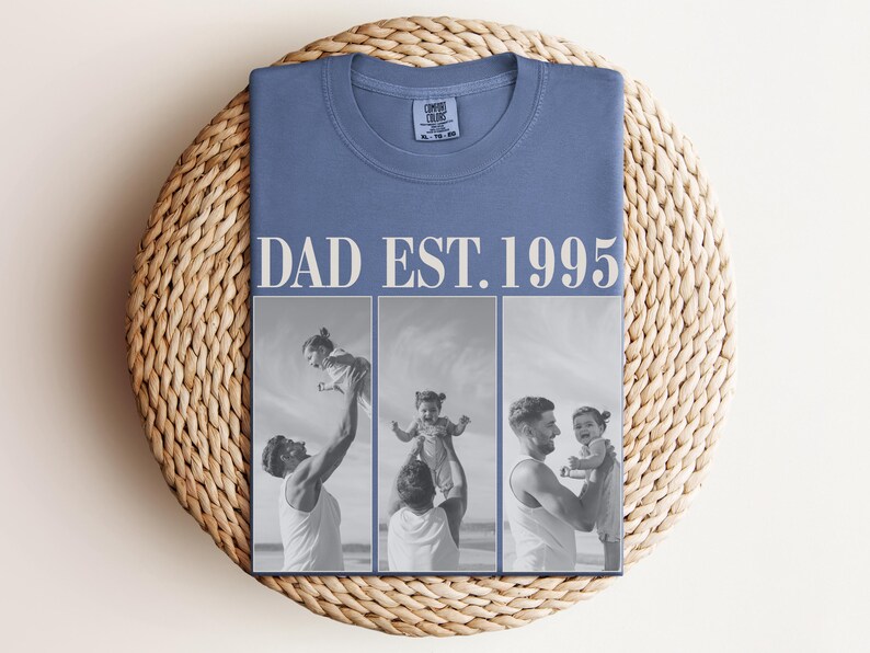 Folded blue unisex t-shirt with ivory “DAD EST. 1995” text and black-and-white three-photo collage showing heartfelt moments between a dad and daughter at the beach. Displayed on a woven round mat in a cozy flat lay style. Perfect custom Father’s Day shirt, birthday gift, or new dad keepsake. Comfort Colors tee with a personal, sentimental touch—ideal for family photo apparel.