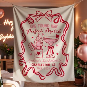 May include: A cream-colored tapestry with a red border and text that reads "She Found Her Perfect Match." The design includes a lighter with flames, a cocktail glass, and hearts. The text also mentions "Andrea's bachelorette, Charleston, SC, MAR. 2026."