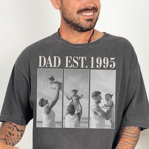 Charcoal unisex t-shirt featuring bold text “DAD EST. 1995” above a custom three-photo collage of a father and daughter. Black-and-white beach images showcase heartfelt moments of fatherhood. Perfect personalized Father’s Day gift, birthday present, or first-time dad keepsake. Oversized fit with a vintage look—ideal for sentimental, stylish, and custom apparel lovers.