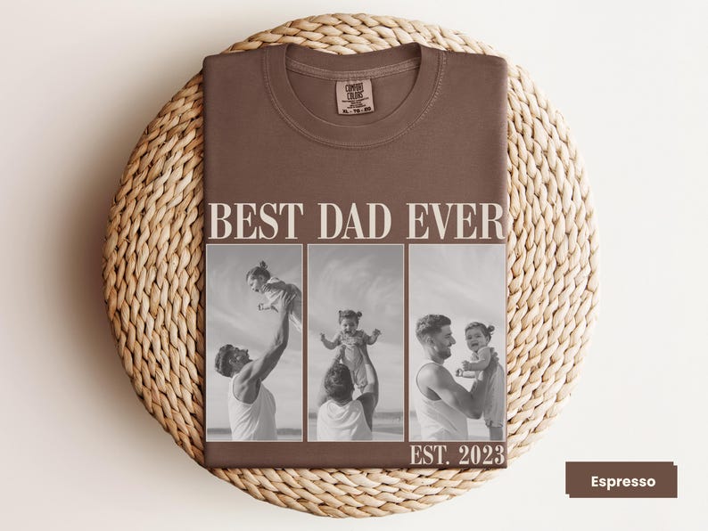 Folded espresso brown Comfort Colors t-shirt with bold “BEST DAD EVER” text and a black-and-white three-photo collage of a father and child, with “EST. 2023” at the bottom. Displayed on a woven mat in a cozy flat lay. Personalized gift shirt for new dads, Father’s Day, or baby’s first birthday. A heartfelt, custom photo tee capturing the love and joy of fatherhood.