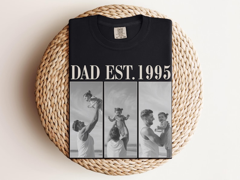 Folded black unisex t-shirt with bold ivory text “DAD EST. 1995” and black-and-white three-photo collage of father and daughter moments at the beach. Displayed on a woven round mat in a flat lay style. Perfect Father’s Day gift, birthday shirt, or new dad keepsake. Soft comfort colors tee with a sentimental, custom design—ideal for personalized dad apparel and photo gifts.