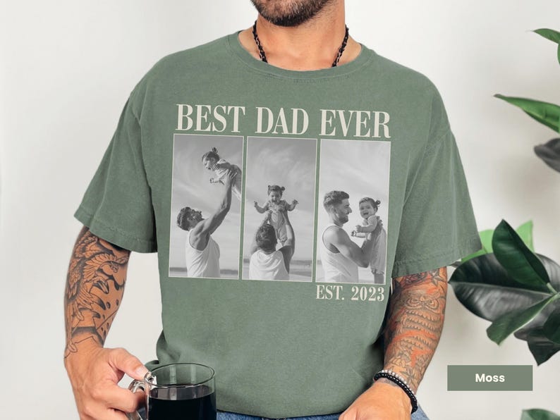 Moss green Comfort Colors t-shirt worn by a man holding a mug, with bold “BEST DAD EVER” text and a black-and-white three-photo collage of a dad with his child, labeled “EST. 2023.” Features sweet candid moments of fatherhood. Personalized shirt perfect for first-time dads, Father’s Day, or baby’s first birthday. A heartfelt and stylish custom gift celebrating dad life.