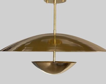 May include: A brass pendant light fixture with two bowl-shaped shades. The top shade is larger and flat, while the bottom shade is smaller and curved.