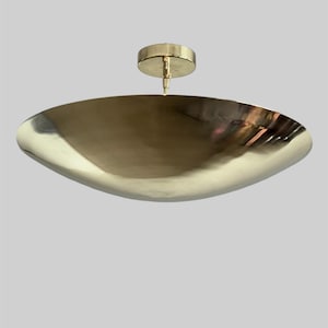 May include: A gold-toned, round, ceiling light fixture with a wide, shallow, bowl-shaped shade.