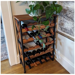 May include: A wooden wine rack with a black metal frame, holding several bottles of wine. The rack has multiple shelves and is topped with a wooden surface. A potted plant with green leaves sits on top of the rack.