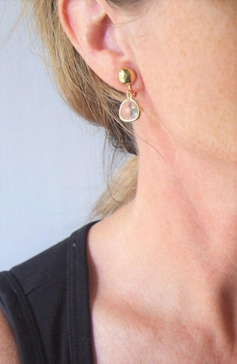 Puede incluir: Pendientes de oro con una gota de cristal transparente. Los pendientes son de un dise&ntilde;o simple y elegante.