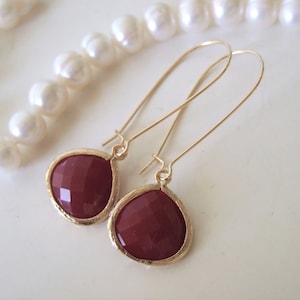 Puede incluir: Un par de pendientes de aro dorados con piedras de color marrón en forma de lágrima.