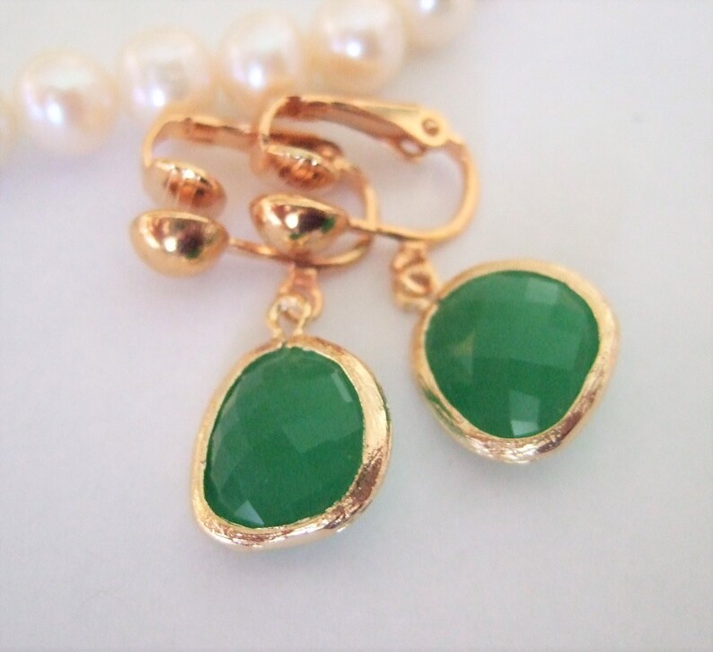 Puede incluir: Un par de pendientes de clip de oro con gotas de piedras preciosas verdes. Los pendientes tienen un dise&ntilde;o sencillo y son perfectos para el uso diario.