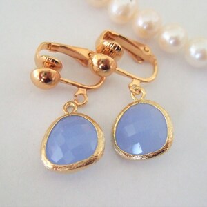 Puede incluir: Un par de pendientes de clip de oro con piedras ovaladas de color azul claro. Las piedras tienen un dise&ntilde;o facetado.