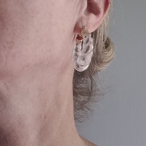 Op de afbeelding: Transparante plastic creolen met een gouden metalen sluiting. De oorbellen zijn ongeveer 5 cm in diameter.