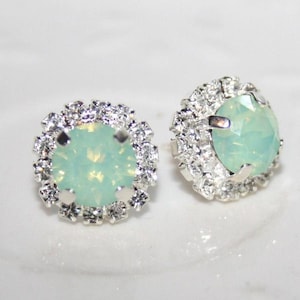 Könnte beinhalten: Ein Paar silberne Ohrstecker mit einem hellgrünen Opal-Mittelstück, umgeben von einem Heiligenschein aus klaren Strasssteinen.