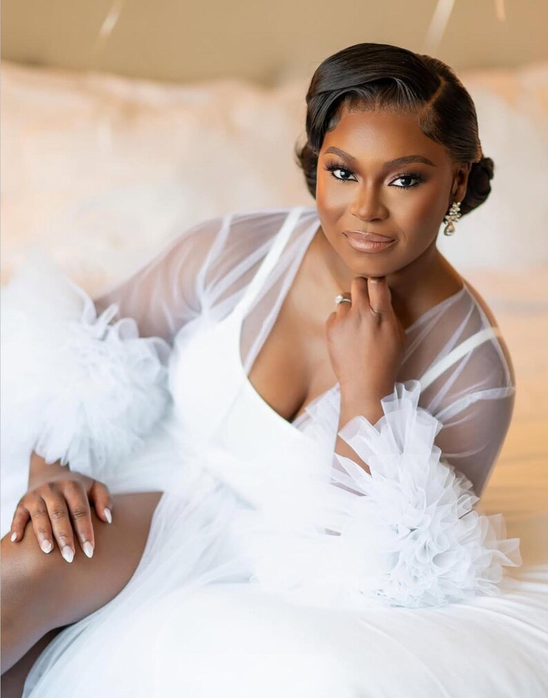 May include: A white tulle robe with ruffled sleeves. The robe is sheer and has a deep V-neckline.