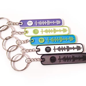 Könnte beinhalten: Fünf bunte Schlüsselanhänger mit verschiedenen farbigen Spotify-Barcodes. Die Schlüsselanhänger sind an silbernen Schlüsselringen befestigt.