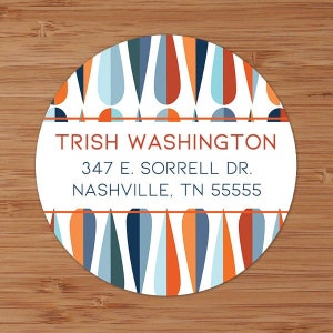 May include: A round sticker with a mid-century modern design. The sticker features a white central band with the name "TRISH WASHINGTON" and an address. The border has a pattern of blue, orange, and white teardrop shapes.