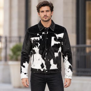 May include: A long-sleeve jacket featuring a black and white cow print pattern. The garment includes a pointed collar, a button-up front closure, two chest pockets with button flaps, and two vertical side pockets. The cuffs also feature buttons.