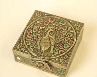 May include: A square, antique-style metal box with a peacock design. The lid features a detailed peacock surrounded by red and green accents. The box has a clasp closure and floral patterns.