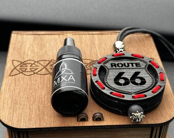 May include: A wooden box with a Route 66 car air freshener and a 10ml bottle of MXA car aroma. The Route 66 emblem is black with red stitching and a black cord. The aroma bottle is black with white text.