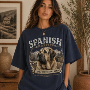 Spanish Mastiff shirt featuring a detailed vintage dog illustration printed on a premium Comfort Colors t-shirt. This oversized graphic tee showcases a loyal and protective mastiff design with rustic mountain and farm elements, perfect for dog lovers, breeders, and large dog owners. Styled in a cozy lifestyle mockup, this aesthetic dog breed shirt makes a unique gift for Spanish Mastiff fans and pet lovers.