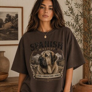 Spanish Mastiff shirt featuring a detailed vintage dog illustration printed on a premium Comfort Colors t-shirt. This oversized graphic tee showcases a loyal and protective mastiff design with rustic mountain and farm elements, perfect for dog lovers, breeders, and large dog owners. Styled in a cozy lifestyle mockup, this aesthetic dog breed shirt makes a unique gift for Spanish Mastiff fans and pet lovers.