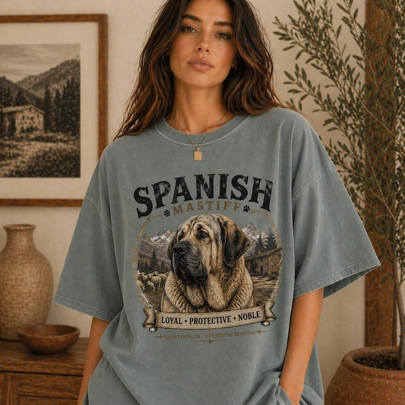 Spanish Mastiff shirt featuring a detailed vintage dog illustration printed on a premium Comfort Colors t-shirt. This oversized graphic tee showcases a loyal and protective mastiff design with rustic mountain and farm elements, perfect for dog lovers, breeders, and large dog owners. Styled in a cozy lifestyle mockup, this aesthetic dog breed shirt makes a unique gift for Spanish Mastiff fans and pet lovers.