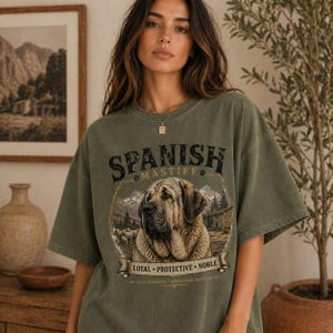 Spanish Mastiff shirt featuring a detailed vintage dog illustration printed on a premium Comfort Colors t-shirt. This oversized graphic tee showcases a loyal and protective mastiff design with rustic mountain and farm elements, perfect for dog lovers, breeders, and large dog owners. Styled in a cozy lifestyle mockup, this aesthetic dog breed shirt makes a unique gift for Spanish Mastiff fans and pet lovers.