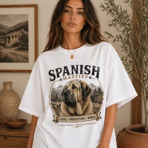 Spanish Mastiff shirt featuring a detailed vintage dog illustration printed on a premium Comfort Colors t-shirt. This oversized graphic tee showcases a loyal and protective mastiff design with rustic mountain and farm elements, perfect for dog lovers, breeders, and large dog owners. Styled in a cozy lifestyle mockup, this aesthetic dog breed shirt makes a unique gift for Spanish Mastiff fans and pet lovers.