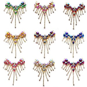 May include: Nine rhinestone brooches in various colors, including green, pink, red, and blue. Each brooch features a central cluster of large, faceted stones with dangling chains of smaller rhinestones.