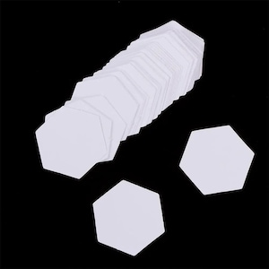 Peut inclure: Une collection de formes hexagonales en papier blanc disposées en une rangée diagonale empilée, avec deux formes hexagonales en papier blanc supplémentaires positionnées séparément sur la surface noire pour montrer le design géométrique plat.