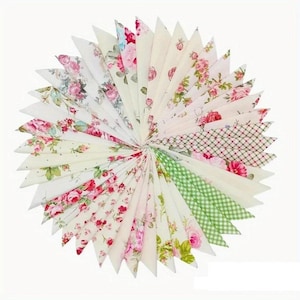 May include: A circular arrangement of fabric pennants in various floral and patterned designs. The pennants feature a mix of pink, red, and green floral prints, along with green gingham and other patterns. The arrangement is set against a white background.